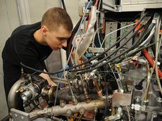 Physiklaborant Till Coester arbeitet am neuen Hybridmotor, der auf dem Prüfstand auf Herz und Nieren getestet wird. (Bild: P. Rüegg / ETH Zürich)